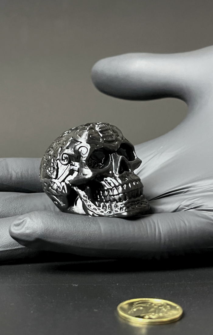 Zbliżenie na czaszke wydrukowaną w technologii żywicznej, dobrze widoczne detale i gładka powierzchnia, czaszka jest trzymana w czarnej nitrylowej rękawiczce.